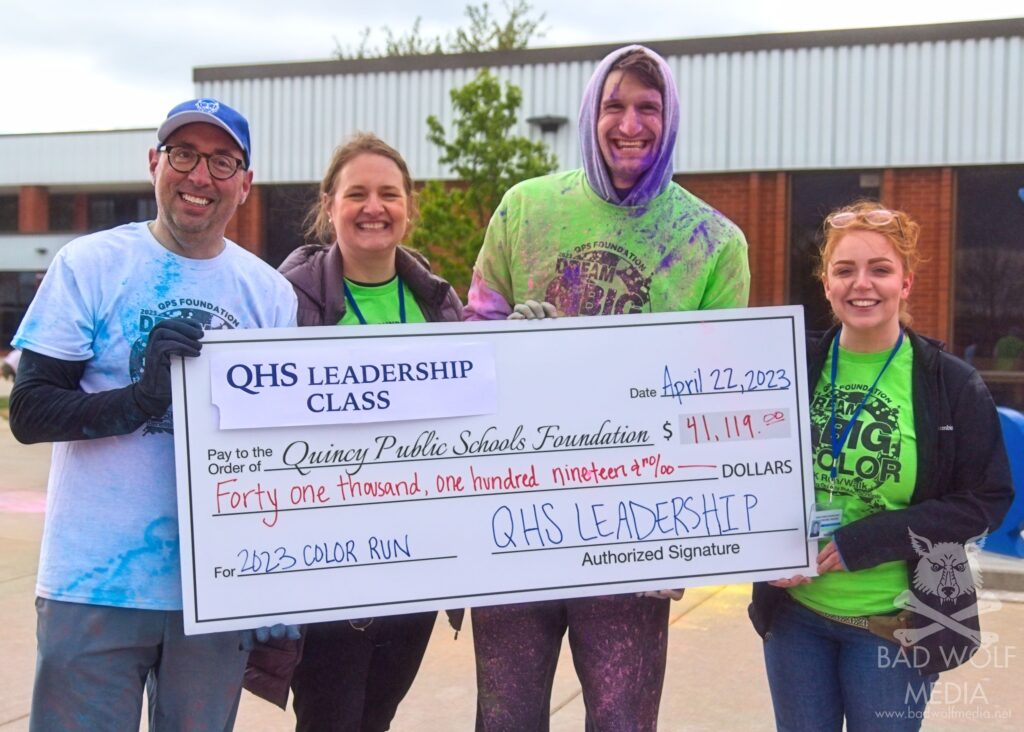 QPS Superintendent Dr. Todd Pettit, QPSF Executive Director Heidi Lanier, QHS Leadership Class Instructor Ben Dombroski, and QPSF Alumni & Events Manager Racheal Raleigh stand with the donation check at the 2023 Dream Big in Color 5K Fun Run. 